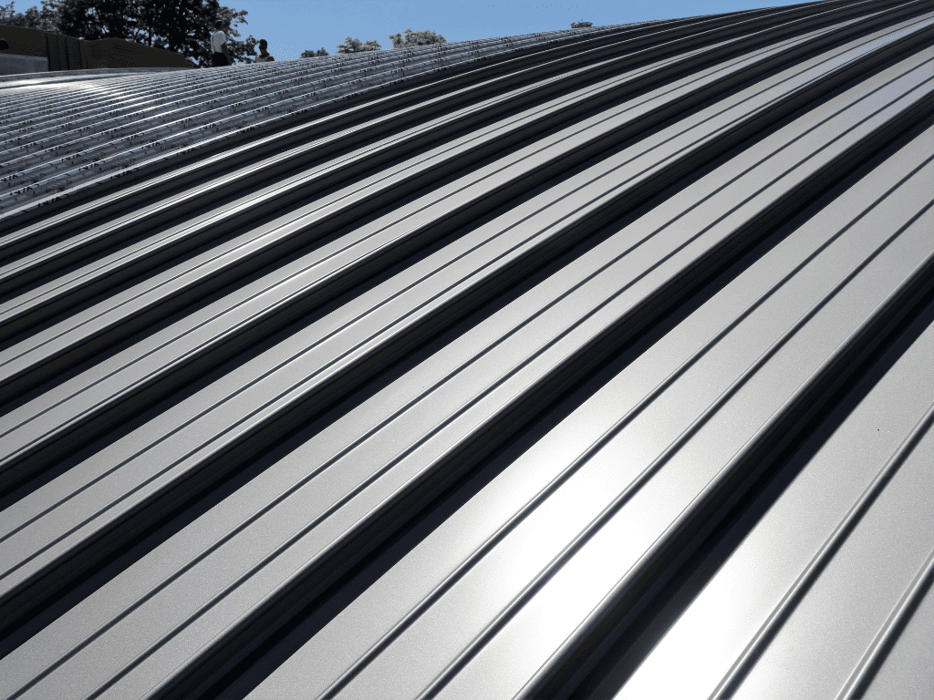 Close-up view of a modern silver standing seam metal roof under bright sunlight, showing clean linear patterns.